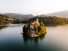 bled-il-lago-si-apre-tra-montagne-morbide-e-verdi-con-lisola-al-centro-e-il-castello-che-domina-lacqua-creando-un-panorama-fiabesco-in-autunno