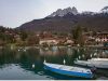 talloires-le-rive-del-lago-di-annecy-accolgono-chalet-in-legno-chiaro-mentre-le-montagne-circostanti-si-tingono-doro-e-rame-in-autunno