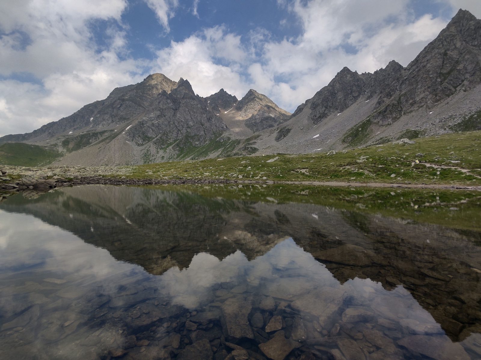 Lago glaciale alpino in estate con riflesso delle montagne piemontesi