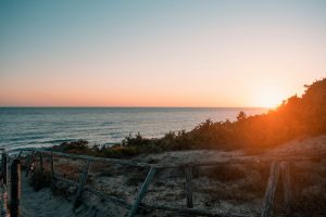 Costa laziale con spiaggia sabbiosa e vegetazione mediterranea al tramonto