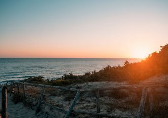 Costa laziale con spiaggia sabbiosa e vegetazione mediterranea al tramonto