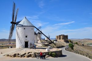 Ciclista su strada rurale aperta in Castiglia-La Mancia con paesaggio di pianura e cielo azzurro