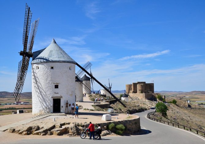 Ciclista su strada rurale aperta in Castiglia-La Mancia con paesaggio di pianura e cielo azzurro