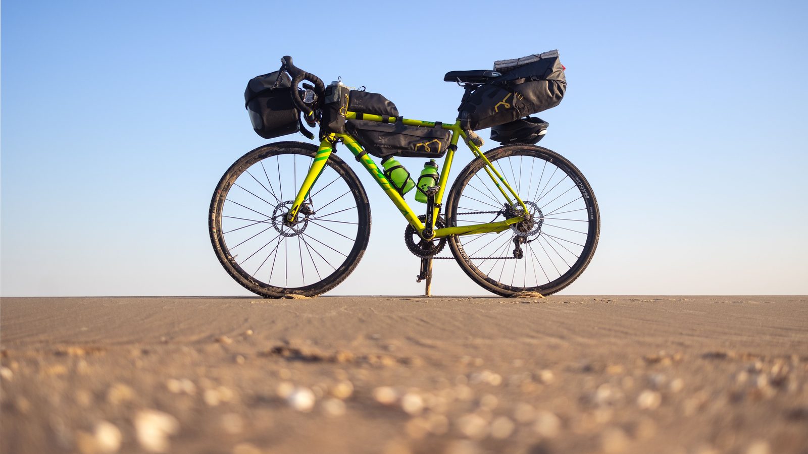 Ciclista con borse da viaggio su strada sterrata in paesaggio arido e soleggiato della Spagna Ciclista con borse da viaggio su strada sterrata in paesaggio arido e soleggiato della Spagna