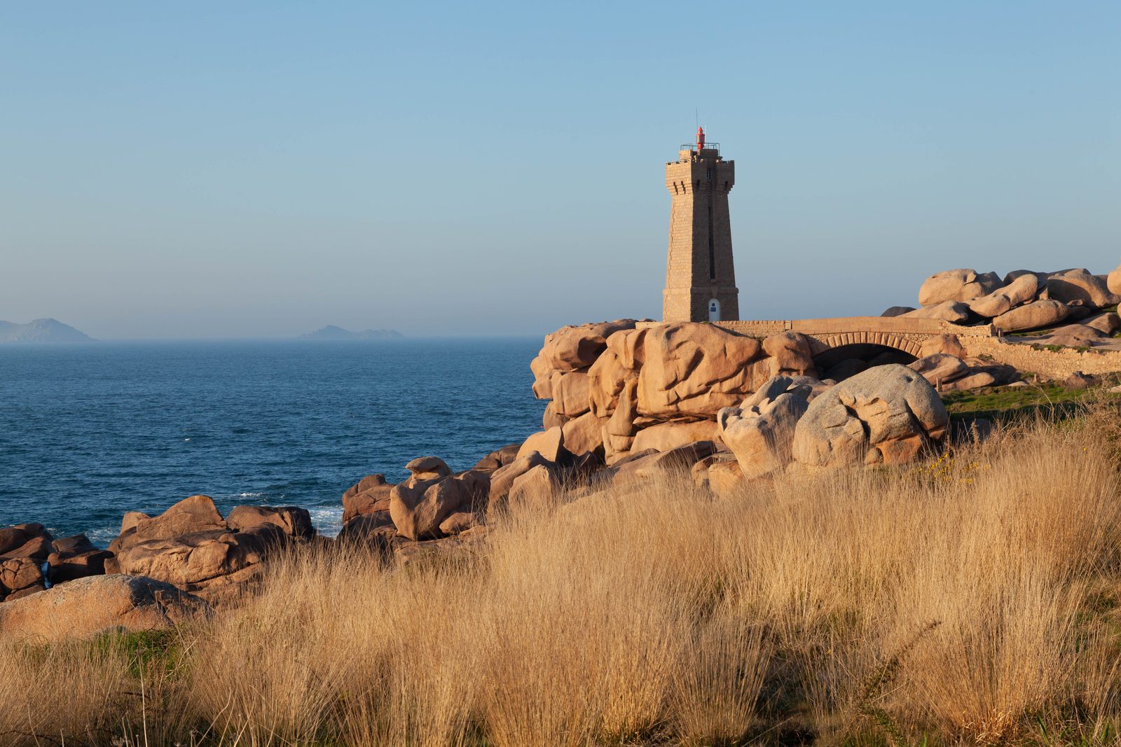 Faro storico sulle scogliere di granito delle isole Scilly al tramonto