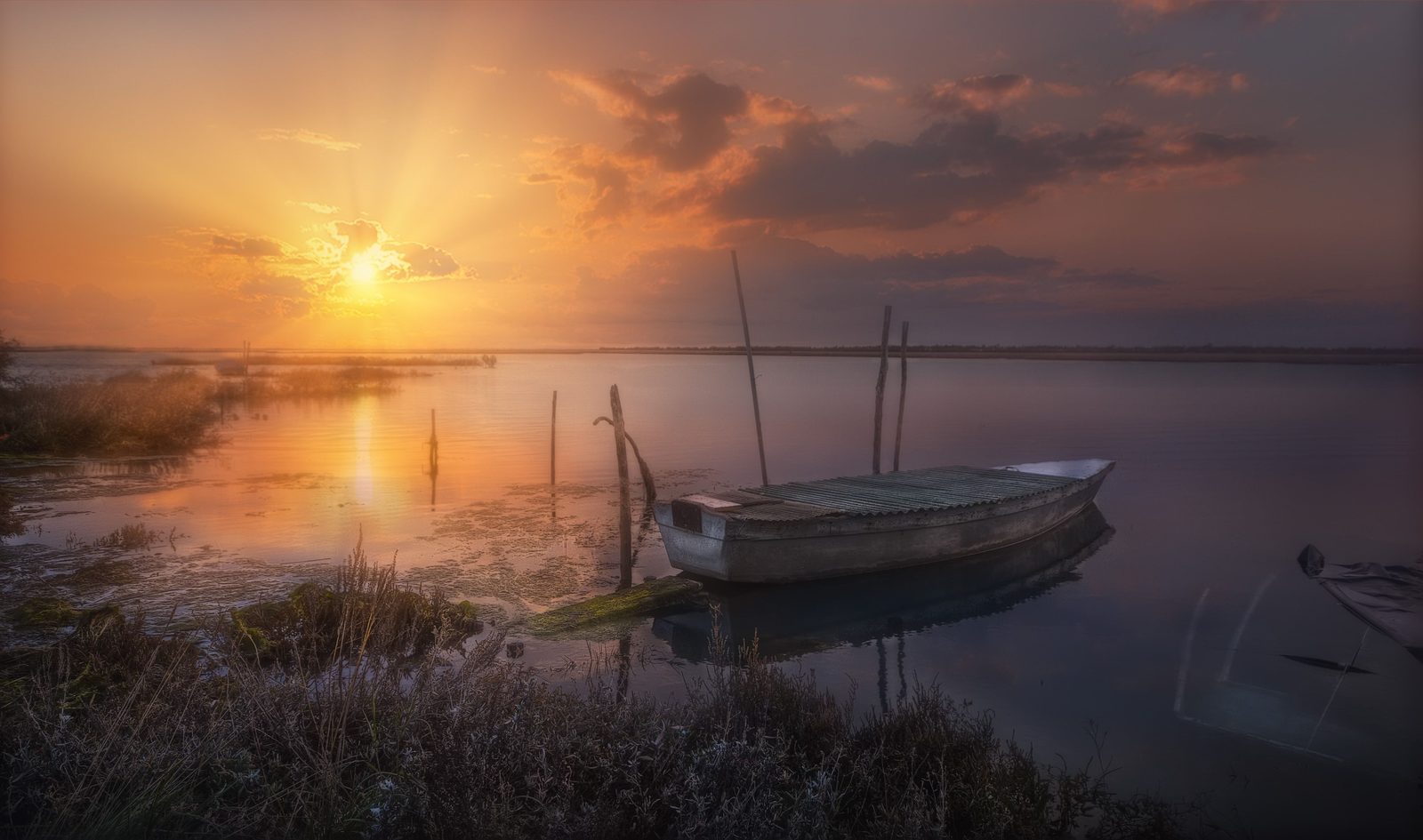 Lago Fusaro al tramonto, specchio d'acqua con vegetazione e cielo colorato