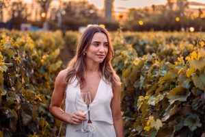 Vigneti autunnali italiani con foglie dorate e calice di vino rosso in primo piano