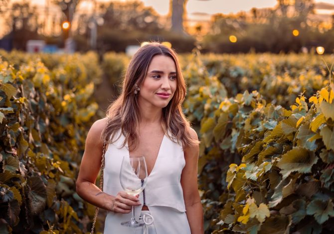 Vigneti autunnali italiani con foglie dorate e calice di vino rosso in primo piano