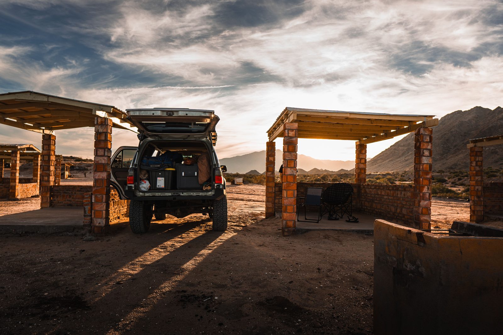 Fuoristrada con tenda sul tetto su strada sterrata rossa namibiana al tramonto Fuoristrada con tenda sul tetto su strada sterrata rossa namibiana al tramonto