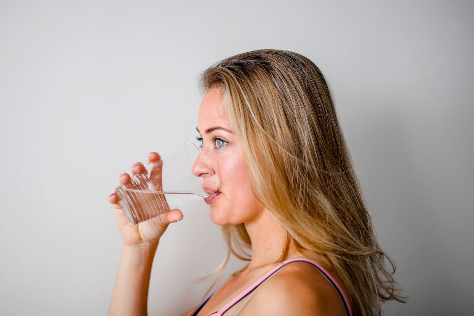 Persona che beve un bicchiere d'acqua con espressione di sollievo
