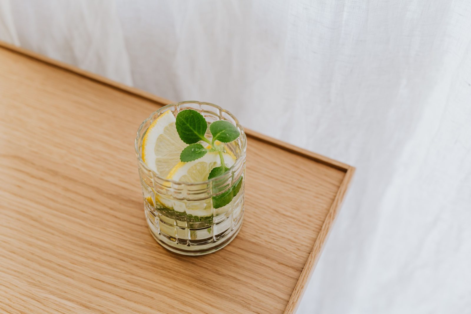 Bicchiere d'acqua fresca con fettine di limone e foglie di menta