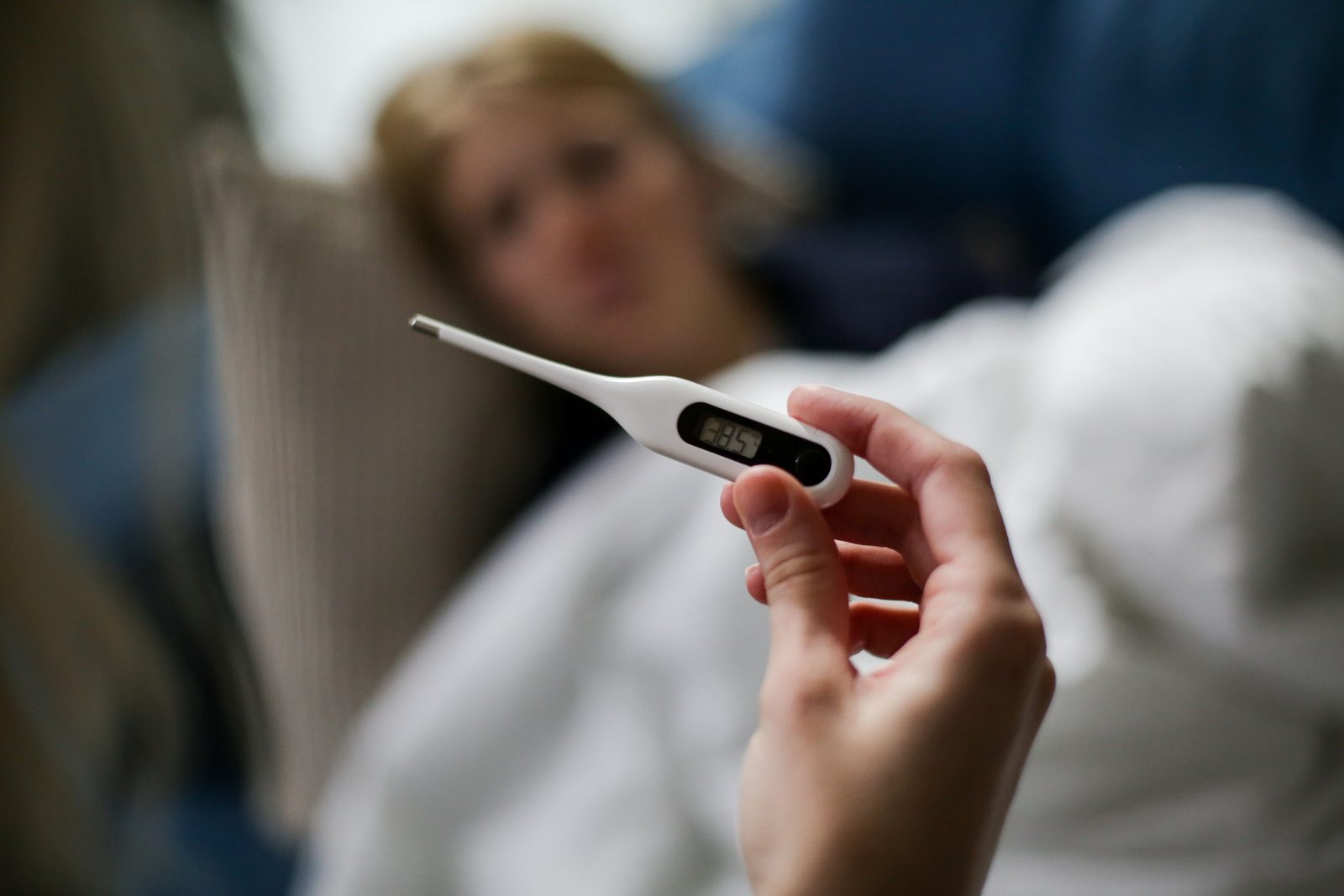 Persona a letto con termometro in bocca, sintomi febbre influenza in inverno Persona a letto con termometro in bocca, sintomi febbre influenza in inverno
