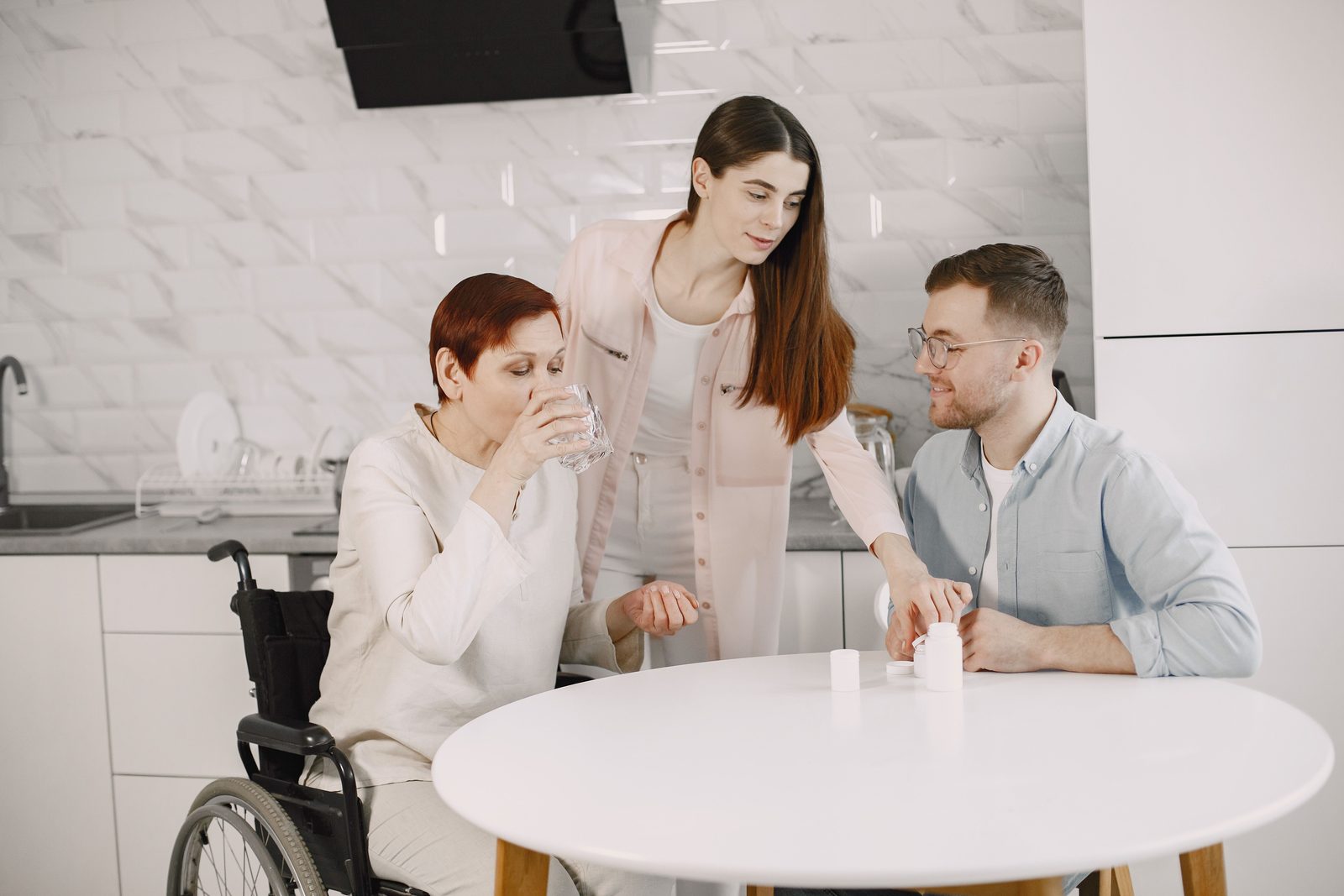 Anziano che beve acqua assistito da un familiare in casa