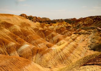 Le colline striate di rosso, arancio e giallo del geoparco Danxia di Zhangye sotto un cielo azzurro